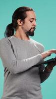 Vertical Portrait of smiling person spending time on laptop, isolated over studio background. Cheerful man checking social media posts on notebook, enjoying leisure time, camera B video