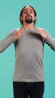 Vertical Portrait of man inhaling and exhaling to relax and gain positive energy, eliminating stress. Person doing breathing exercises for wellbeing, isolated over studio background, camera A video