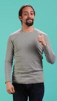 Vertical Cheerful man showing thumbs up sign gesturing, exulting happy facial expression and satisfaction. Joyful person being excited, doing approving hand gesture, studio background, camera A video