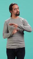 Vertical Portrait of assertive man asking for timeout, doing hand gestures, feeling fatigued. Unhappy person doing vehement pause sign gesturing, wishing for break, studio background, camera A video