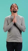 Vertical Pious man praying to his god, asking for forgiveness. Spiritual person doing worship hand gesturing, confessing, begging for pardon, isolated over studio background, camera A video