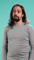 Vertical Portrait of spiteful man making exaggerated silly faces, mimicking someone, doing mocking gesturing. Person making goofy facial expressions, being playful, making fun, studio background, camera B video