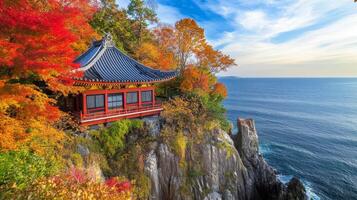 Japanese Pagoda Perched on a Cliff Overlooking the Ocean with Autumn Foliage photo