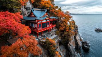 Red Japanese Temple Perched on a Cliffside Overlooking the Ocean photo
