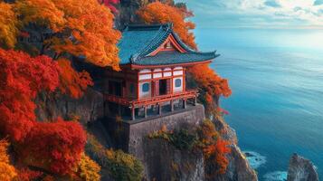 Traditional Japanese Temple Perched on Cliffside Overlooking the Sea During Autumn photo