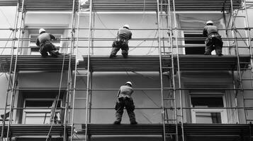 Four Construction Workers on Scaffolding Around Windows of a Building photo