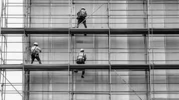 Three Construction Workers on Scaffolding During Building Renovation photo