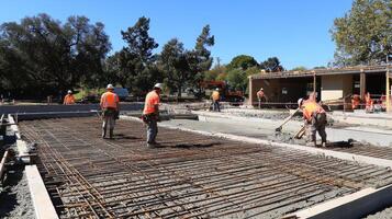 Construction Workers Pouring Concrete on a Foundation with Rebar photo