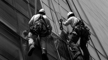 Two window washers hanging from a skyscraper photo