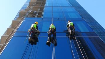Three Window Washers Suspended on Ropes Cleaning a Tall Glass Building photo