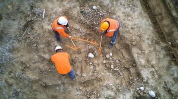 Three Construction Workers Marking an Area on a Gravel Ground photo