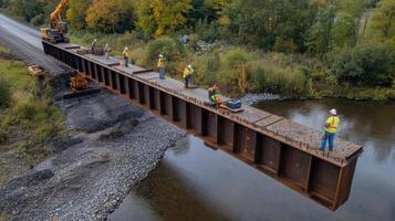 Construction Workers Installing Steel Beam for New Bridge Over River photo