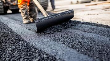 Worker Spreading Fresh Asphalt with a Rake photo