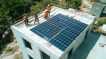 Workers Installing Solar Panels on a New Building Roof photo