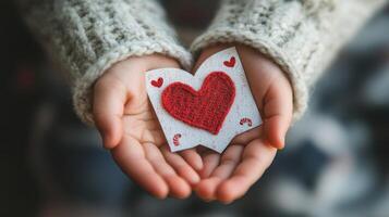 Child's Hands Holding a Red Heart on White Paper photo