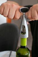 Hands using a wine corkscrew to open a bottle, related to celebrations and social gatherings photo
