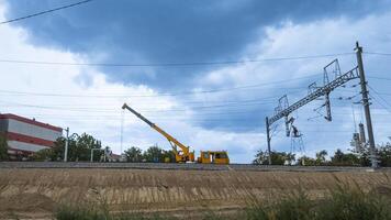 Construction site with heavy machinery and workers installing railway powerlines under a cloudy sky, illustrating infrastructure development photo