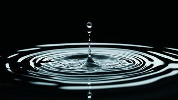 Extreme close up of a single raindrop landing on a reflective surface causing ripples photo
