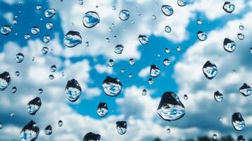 Drops of water on a glass surface reflecting a blue sky with fluffy clouds photo