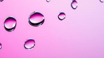 Drops of water on glass creating abstract shapes with a gradient pink and purple background photo