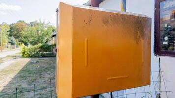 An old, rustic yellow mailbox on a sunny countryside road highlighting nostalgia and traditional mail, suitable for summertime themes photo