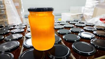 A jar of golden honey on top of other jars in a factory, symbolizing Thanksgiving preparations and organic food production photo