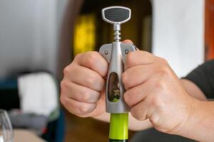 A person uses a corkscrew to open a wine bottle, ideal for celebration, relaxation, or holiday gatherings photo