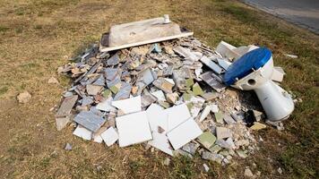 A pile of construction debris and an old toilet discarded improperly, highlighting the issue of illegal dumping and waste management problems photo