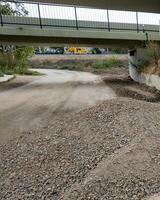 Underpass construction zone with gravel piles and machinery representing infrastructure development and roadwork challenges photo