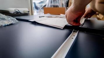 Person assembling furniture with instructions in a home improvement setting, focusing on DIY tasks and interior design photo
