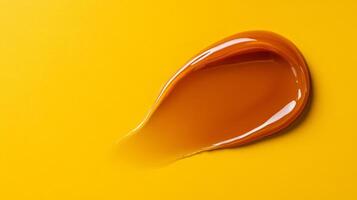 Burnt sienna lip balm smear with soft gloss texture isolated on a soft gradient of mustard yellow photo