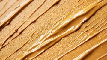 Closeup of golden brown eyebrow gel with tiny microfibers creating a textured pattern against a light tan background photo