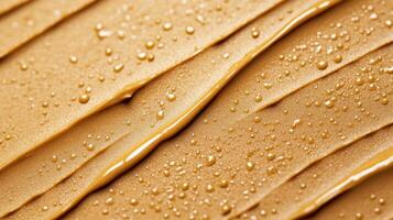 Closeup of golden brown eyebrow gel with tiny microfibers creating a textured pattern against a light tan background photo