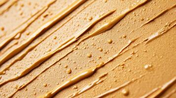 Closeup of golden brown eyebrow gel with tiny microfibers creating a textured pattern against a light tan background photo