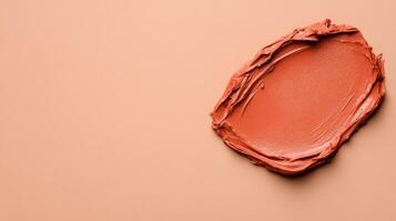 Closeup of terracotta clay mask smeared in rough organic lines on a smooth beige background photo