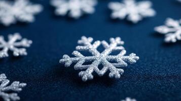Closeup of translucent snowflake shaped highlighter particles scattered across a deep navy blue surface photo