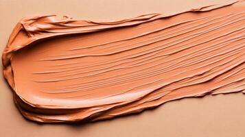 Creamy texture of spiced orange foundation swatch softly melting into an almond colored background photo
