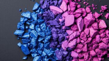 Crushed jewel toned eyeshadow powders in sapphire and amethyst shades creating a colorful textured background photo