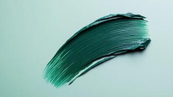 Deep evergreen eyeliner stroke with a matte finish isolated against a pale frosty grey background photo