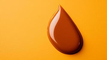 Glossy caramel lip gloss in a thick luminous droplet with highlights catching warm light on a creamy background photo