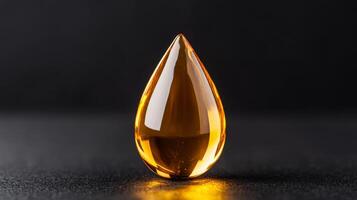Golden facial oil drop glistening against a matte black background capturing light through its transparent form photo