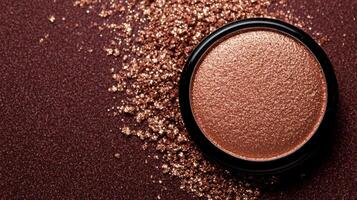 Macro of warm taupe eyeshadow with hints of gold sparkles blending into a deep plum background photo