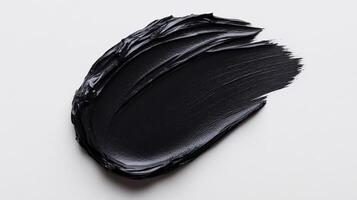Matte black cosmetic clay mask spread in smooth thick lines on a stark white background with subtle texture photo