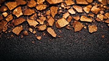 Metallic bronze eyeshadow spread in fine grains with varying shades of copper and gold textured against a dark surface photo
