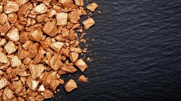 Metallic bronze eyeshadow spread in fine grains with varying shades of copper and gold textured against a dark surface photo