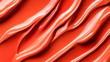 Swirls of rich coppery red liquid lipstick creating an abstract pattern on a soft muted orange background photo