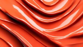 Swirls of rich coppery red liquid lipstick creating an abstract pattern on a soft muted orange background photo