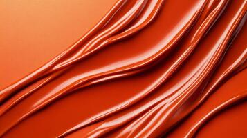Swirls of rich coppery red liquid lipstick creating an abstract pattern on a soft muted orange background photo