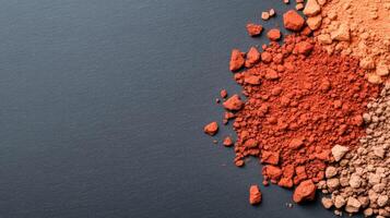 Textured palette of umber and rust cosmetic powders scattered on a slate grey background with an autumn feel photo