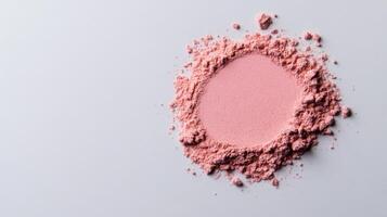 Warm blush powder in a soft muted mauve shade lightly dusted on a pale grey background photo